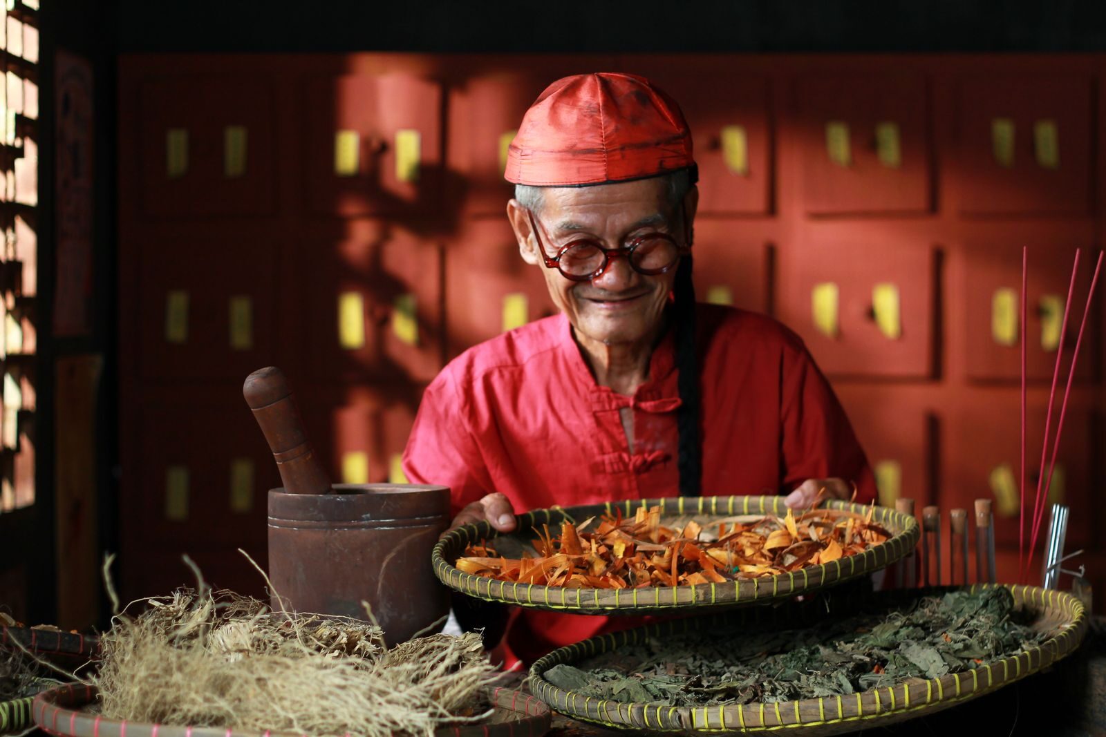 Senior herbalist preparing traditional remedies with dried herbs in Jakarta, Indonesia.
